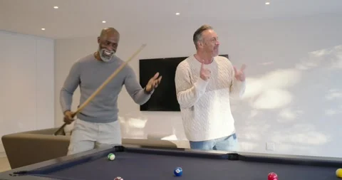 Diverse men at pool table watching senior man striking cue, scattering balls, Stock Footage 342259152