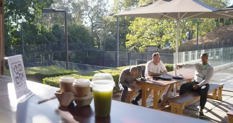 Diverse men sitting table server coming African American man paying with phone Stock Footage 341953678