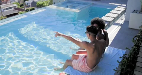 Diverse men spotting movement, pointing and talking, sitting on towel at rooftop Stock Footage 342392905