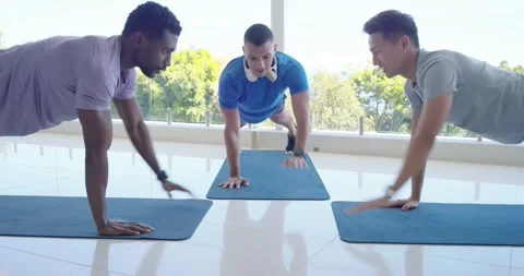 Diverse men starting low doing pushups center doing plank left dropping resuming Stock Footage 335780743