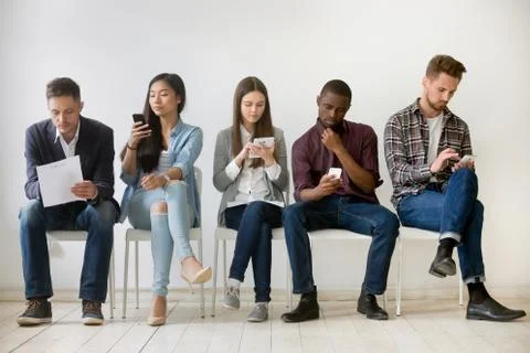 Diverse millennial people waiting in queue holding resumes using Stock Photos