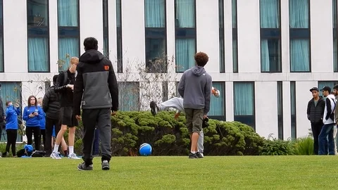Diverse multi-ethnic group of kids playing football in public, urban, city Stock Footage