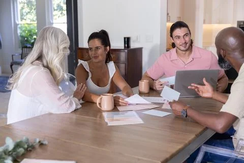Diverse multi-generation family discussing paperwork at dining table with laptop Stock Photos