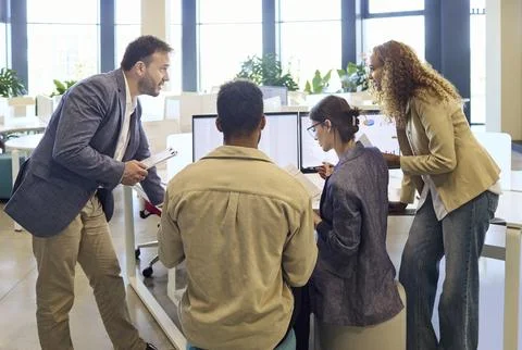 Diverse office team in active discussion around computer screens during planning Stock Photos