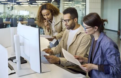 Diverse office team collaborating at computer during meeting planning discussion Stock Photos