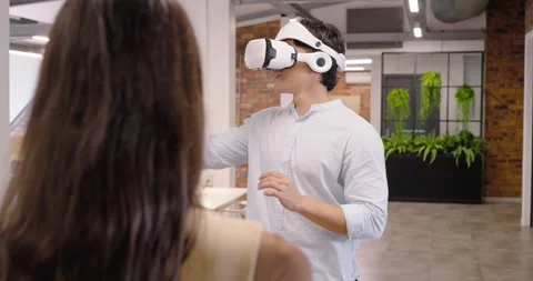 Diverse office team demoing VR, Asian man wearing white VR headset reaching Stock Footage 340147869