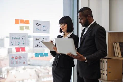 Diverse office workers checking data using electronic device Stock Photos