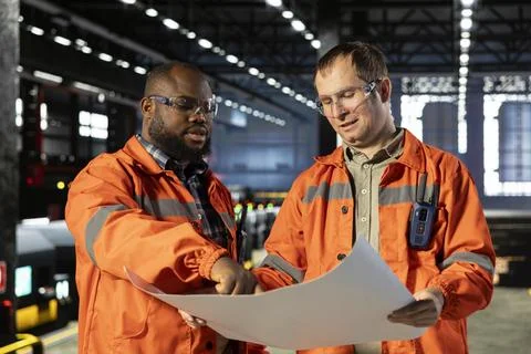 Diverse operators handling assembly workflow with industrial plans Stock Photos
