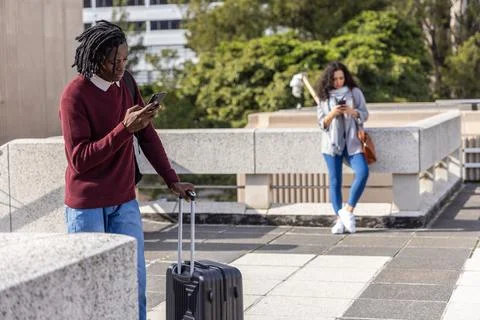 Diverse pedestrians standing on rooftop checking phones near suitcase and Photos