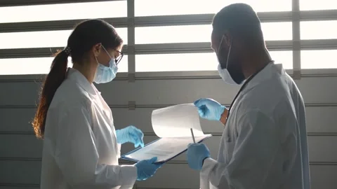 Diverse physicians discussing patient medical tests holding clipboard Stock Footage