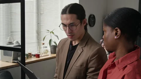 Diverse Programmers Collaborating on Laptop in Modern Office 库存影片 336719409