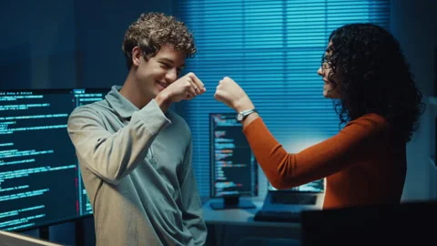 Diverse programmers give fist bump to celebrate success in dark office at night. Vídeos de archivo 347148623