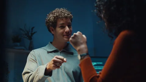 Diverse programmers give fist bump to celebrate success in dark office at night. Vídeo Stock 347148626
