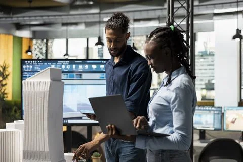 Diverse real estate developers study architectural 3D models for city planning Stock Photos