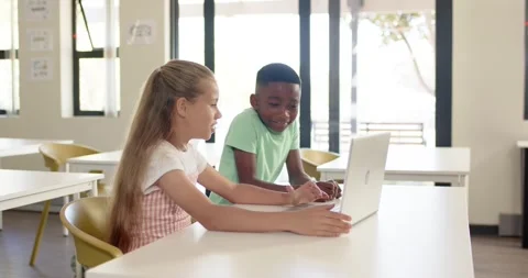Diverse school-age classmates working on laptop in class for task girl pointing Stock Footage 335927847