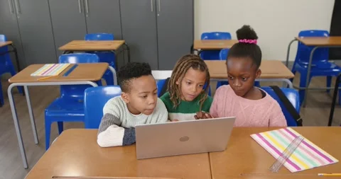 Diverse school-aged students leaning toward open laptop, typing and using Stock Footage 341029665