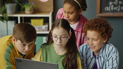 Diverse School Children Collaborating on Laptop in Classroom Stock Footage 340549228