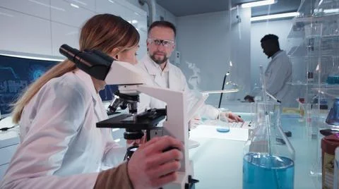 Diverse scientists testing blue liquid in laboratory 스톡 사진