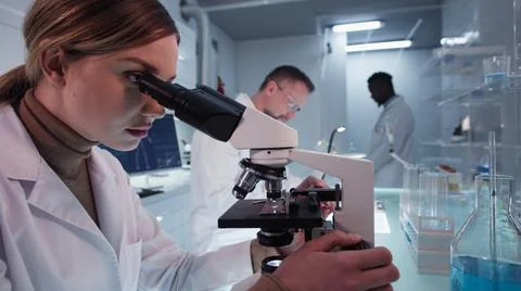 Diverse scientists testing blue liquid in laboratory Stock Photos