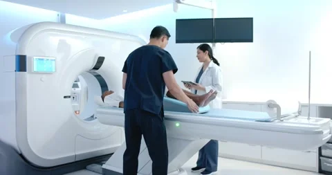 Diverse scrub staff placing African American patient on pad after tablet check Stock Footage 341736436