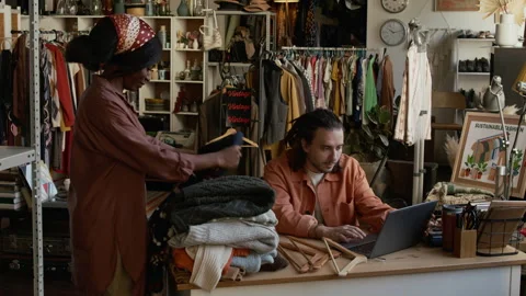Diverse Second Hand Shop Workers Folding Clothes and Chatting Video stock 327815132
