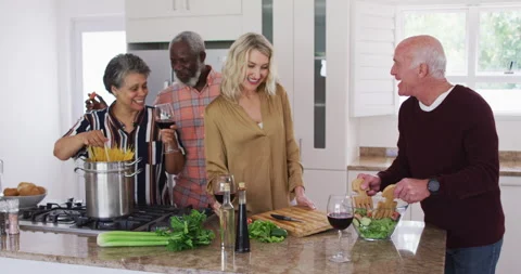 Diverse senior couples preparing vegetable salad in a kitchen Видео 146558989