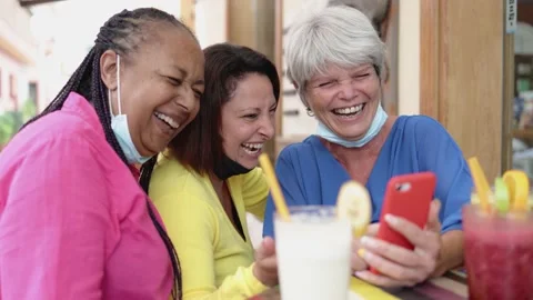 Diverse senior friends using mobile phone at brunch restaurant with masks under Stock Footage 163374064
