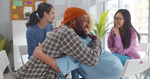 Diverse smiling people hugging in support group meeting Stock Footage 154147150