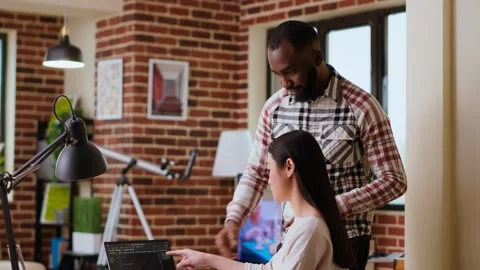 Diverse software developers team coding on a laptop in a cozy home office Stock Footage 319721502