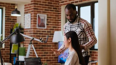 Diverse software developers team coding on a laptop in a cozy home office Stockfoto's