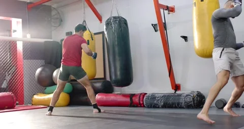 Diverse sparring partners wrapping hands and practicing heavy bag drills in gym Stock Footage 344325050