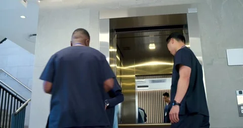 Diverse staff stepping out in lobby as elevator opening with colleague Stock Footage 344331072