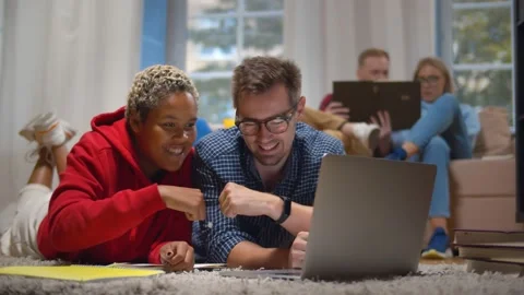 Diverse student working on project together gesturing fist bump lying on floor Stock Footage 139220199