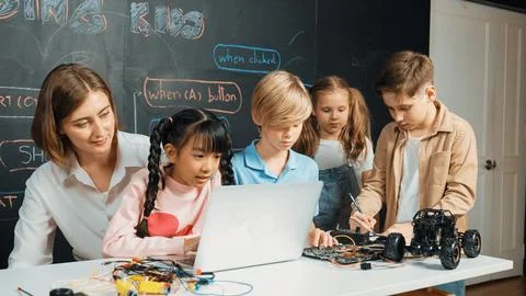 Diverse student writing engineering code while boy fixing board. Erudition. Foto stock
