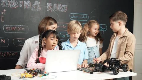 Diverse student writing engineering code while boy fixing board. Erudition. Stock Photos