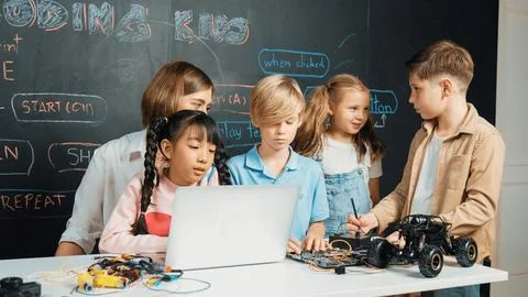 Diverse student writing engineering code while boy fixing board. Erudition. Stock Photos