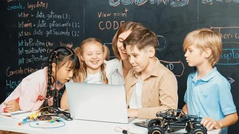 Diverse student writing engineering code while boy fixing board. Erudition. Stock Photos