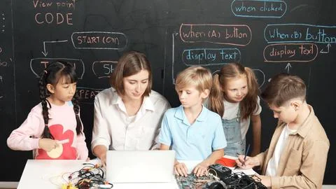 Diverse student writing engineering code while boy fixing board. Erudition. Foto stock