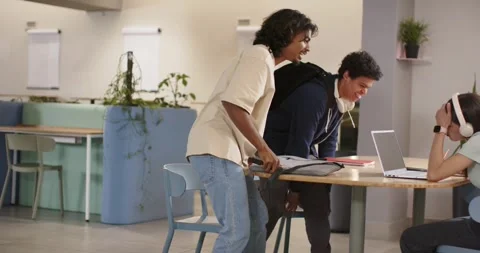 Diverse students arriving, man swinging gray bag onto round table, preparing Stock Footage 339651660