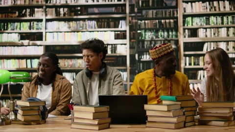 Diverse students discuss classwork during group study around library table Stock Footage 337229601
