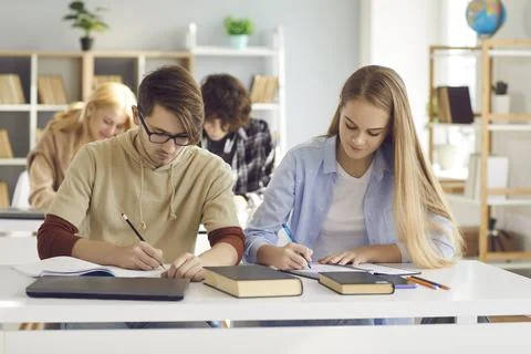 Diverse students at shared desk making notes studying together at university Stock-Fotos