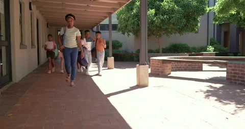 Diverse students walking in school corridor, bell ringing, lead girl in green Stock Footage 341937684