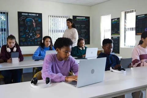 Diverse students working as female student typing on silver laptop in purple Stock-Fotos