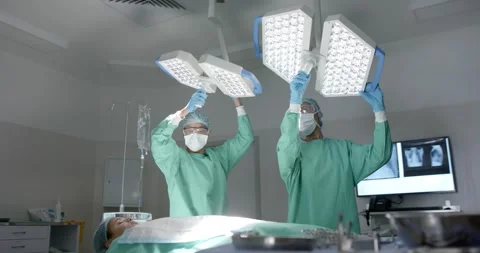 Diverse surgeons with face masks preparing surgery in operating room in slow Vídeo Stock 341239984