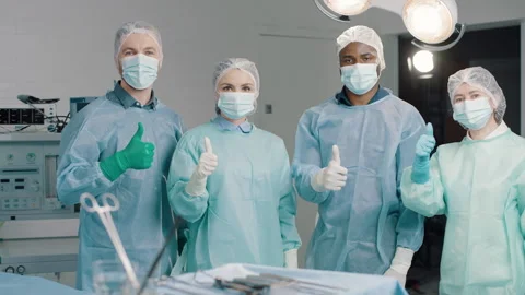 Diverse surgical team in operating room give a thumbs up 스톡 동영상 280111857