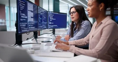 Diverse Team Of Agile Software Engineers Coding On Multiple Computer Monitors Foto stock