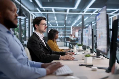 Diverse Team Of Analysts And Managers Review Data Dashboards In Office Foto stock