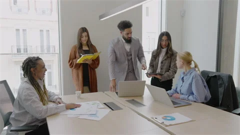 A diverse team collaborates in a bright, creative office to strategize their Video stock 306044145