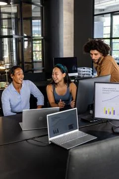 Diverse team collaborating on project with laptops and charts in modern office 写真素材