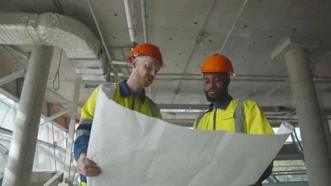Diverse team of construction engineers working on building site examining Stock Footage 137313020